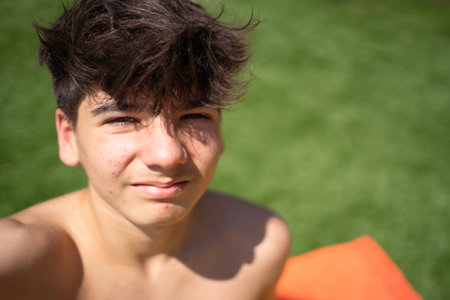 Selfie of a teenager boy relaxing outdoors on summer day: portrait of happy adolescent boy enjoying sunlight with copy spaceの写真素材