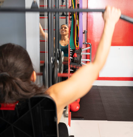 Close up of sportswoman exercising back muscles using training apparatus in gymの写真素材
