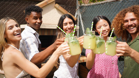 Cheerful multi-ethnic friends enjoying a refreshing lemonade toast at a summer backyard partyの写真素材