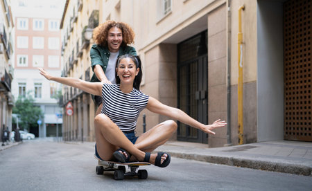 Young man girlfriend pushing on skateboard while having fun in urban street