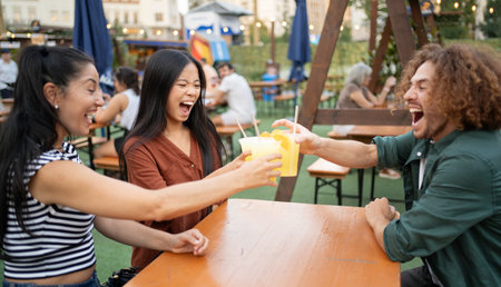 Happy multiethnic friends are toasting with lemonade at outdoor beer gardenの写真素材