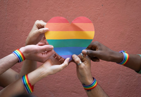 Close up of activists holding rainbow heart and wearing rainbow bracelets: celebrating lgbtq prideの写真素材