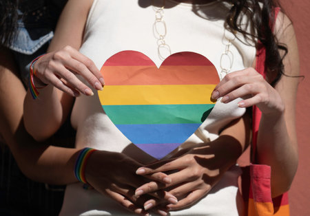 Close up of young woman embracing, holding a rainbow heart, symbolizing lgbtq pride, love, and...