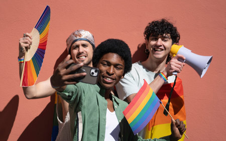 Multiethnic group of young activists taking selfie and holding rainbow flags and megaphone at a pride paradeの写真素材