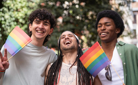 Multiethnic friends laughing and enjoying gay pride parade holding rainbow flags