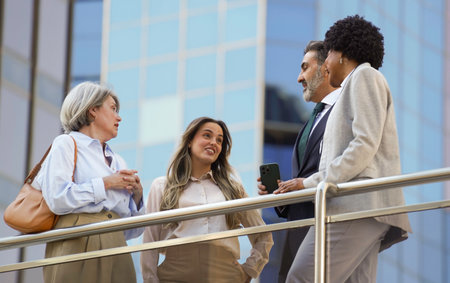 Business team having informal conversation outside office building during breakの写真素材