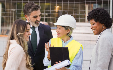 Female architect explaining building project to investors and managers using blueprint and tabletの写真素材