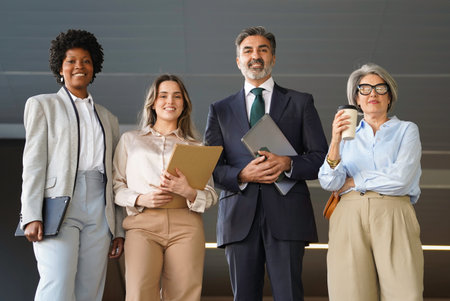 Diverse group of business professionals standing together in a modern office, representing teamwork,...