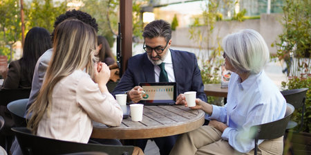Business team analyzing financial charts on a tablet during a meeting at an outdoor cafe