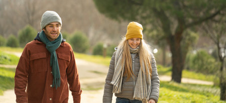 Young couple wearing winter clothes enjoying a walk in a park during a sunny winter day with copy spaceの写真素材