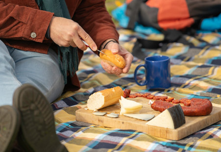 Hiker enjoying a picnic with cheese, sausage, bread and coffee