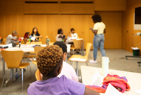 Afro diverse children listening to a teacher in a modern classroom setting