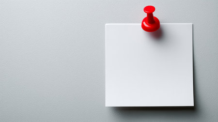 Blank note paper holding with a red pushpin on a textured gray backgroundの写真素材