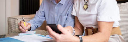 Older couple budgeting expenses, calculating savings, and managing retirement plan with smartphone