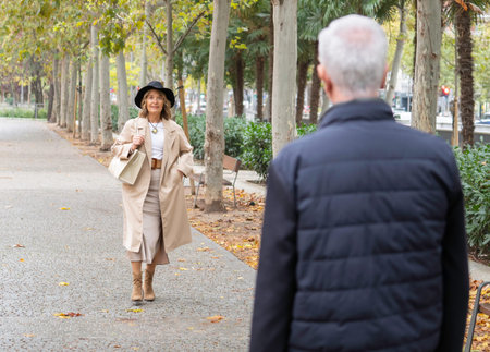 Senior woman walking in park, meeting a man, enjoying an autumn dayの写真素材