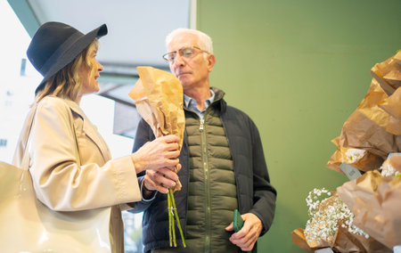 Senior couple examining a bouquet of flowers wrapped in paper at a flower shopの写真素材