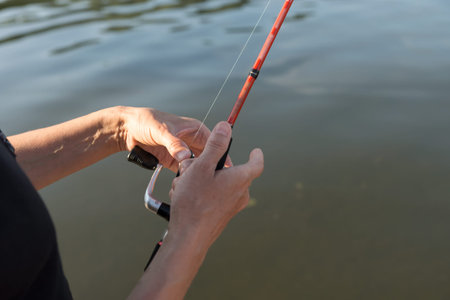 Fisherman's hands hold a  spinning over the water while fishing.の写真素材
