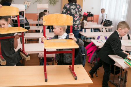 First-graders put chairs on the desk at the end of lessons at rural primary school.のeditorial素材