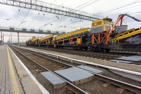 Freight train with industrial equipment stands on the tracks of a junction railway station with rails in the foreground.の写真素材