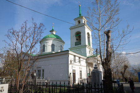 People walk near the Holy Trinity Cathedral (1836) of the Krasnoyarsk city, in the spring afternoon.