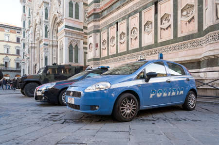 Police vehicle stands near the entrance to the Cathedral of Santa Maria del Fiore (1296 - 1436) at the Cathedral square (Piazza del Duomo) in Florence, Italy.のeditorial素材
