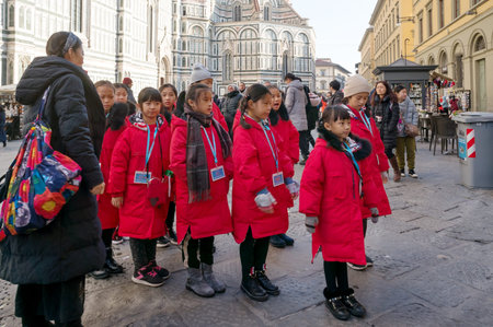 Florence, Tuscany. Italy Tour group of Asian girls stands near Medieval religious building of the baptistery of San Giovanni (1059-1129) at the Cathedral square (Piazza del Duomo)のeditorial素材