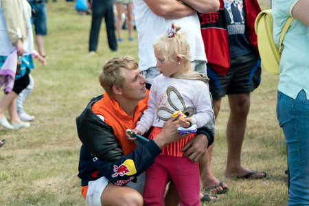 Dad, squatting, talking with a little daughter in a clearing, among people.のeditorial素材