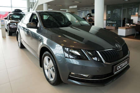 A black new car stands in the showroom of a car dealership next to a column.のeditorial素材