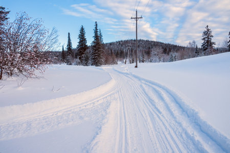 Winter landscape with a ski road between the snowdrifts and the setting sun.の写真素材
