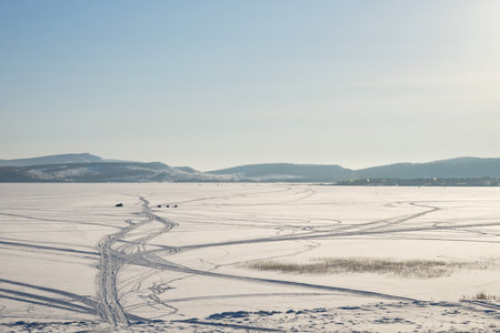 Fishermen catch fish on the Great Frozen Lake, against the backdrop of the mountains, in winter.の写真素材