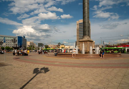 Krasnoyarsk, Krasnoyarsk Region, RF - July 19, 2021: People rest at the fountain in the Railway Station Square against the backdrop of the city near the main railway station on a sunny summer day.のeditorial素材