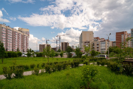 Krasnoyarsk, Krasnoyarsk Region, RF - July 1, 2021: View of a residential neighborhood with parked cars and the construction of new buildings in the distance on a summer day.のeditorial素材