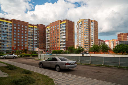 Krasnoyarsk, Krasnoyarsk Region, RF - July 1, 2021: Cars drive through the courtyard of high-rise apartment buildings past a hockey rink on a cloudy summer day.のeditorial素材