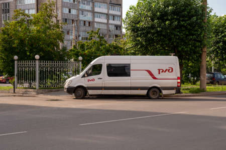 Krasnoyarsk, Krasnoyarsk Region, RF - July 19, 2021: A minibus with the logo of the Russian Railways company stands parked on the side of the road near a metal fence on a sunny summer day.のeditorial素材