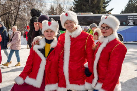 Krasnoyarsk, Krasnoyarsk Region, RF - March 14, 2021: Smart young people in Russian folk costumes stand among a crowd of people at the Farewell to Winter holiday in the city park.のeditorial素材