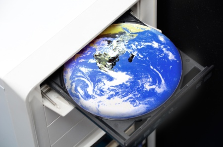 Planet Earth in a CD tray of a desktop computer.の写真素材