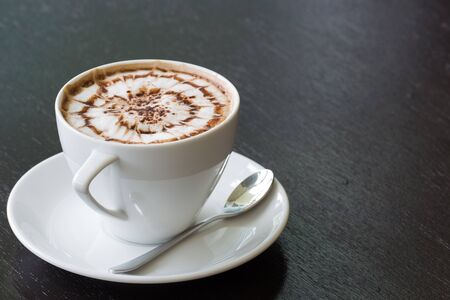 cup of coffee with spider design on black wood tableの写真素材
