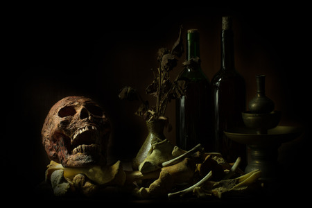 Still Life Skull , Bone ,Wine Bottles and flower on Old Wood Table Background -Halloween or Esoteric Conceptの写真素材