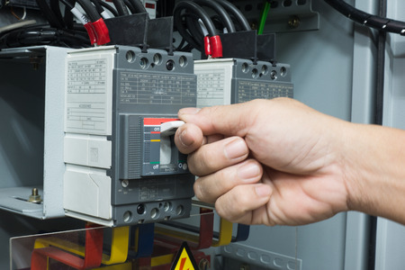 Hand of Engineer turning on switch in the electrical cabinet at control roomの写真素材