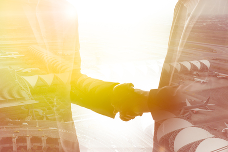 Teamwork concept. Close up of handshake on abstract city background. Double exposure.の写真素材