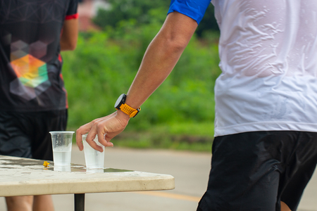 Marathon runner picking up water at service pointの写真素材