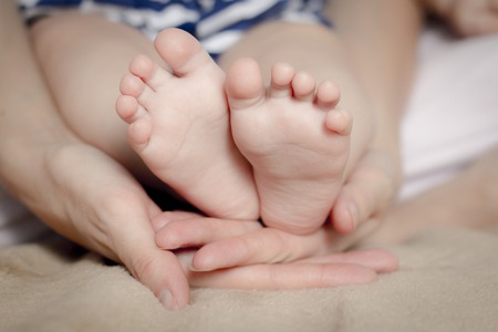 Gentle touch. Woman holding tiny baby feet in her handsの写真素材