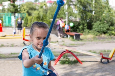 Happy smile boy and girl ride on the swings at the playground on the streetの写真素材