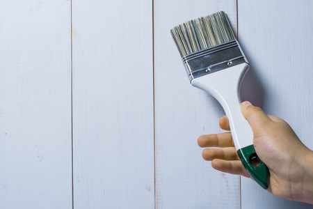 Baby hand holds a paint brush on a white wooden backgroundの写真素材