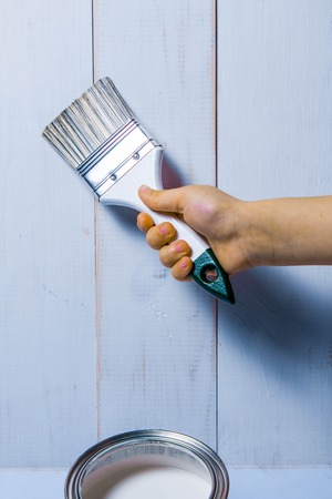 Baby hand holds a paint brush on a white wooden backgroundの写真素材