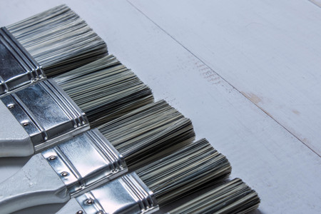 White paint brushes and a can of oil paint on a wooden tableの写真素材