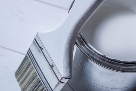 Paint brush on a can of paint on a wooden table textureの写真素材