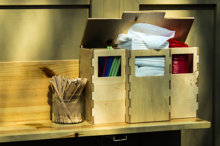 Napkins, straws, wooden sticks for stirring coffee in wooden stands in a summer cafe on the street