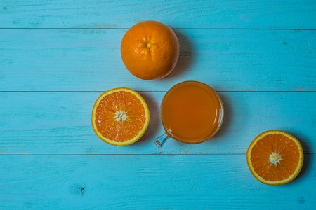 A glass of fresh orange juice with sliced oranges on a wooden table. Preparation of fresh orange juiceの写真素材