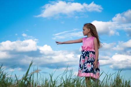 Portrait of a seven year old girl in a bright pink dress on the grass in the parkの写真素材